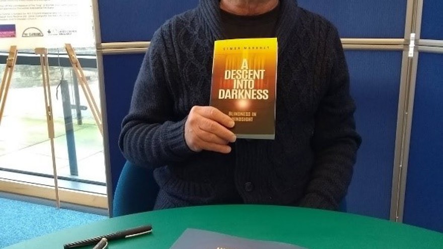 Blind veteran, Simon, holding up a copy of his first book at the launch event