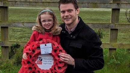 Graeme knelt down next to his young daughter who is holding a poppy wreath