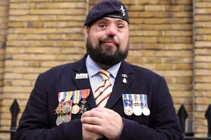 Photo of blind veteran Simon wearing his service medals