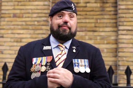 Photo of blind veteran Simon wearing his service medals