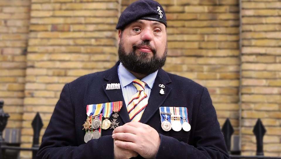 Photo of blind veteran Simon wearing his service medals