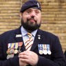 Photo of blind veteran Simon wearing his service medals