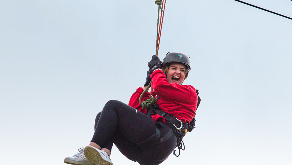 A photo of a girl going down a zip wire