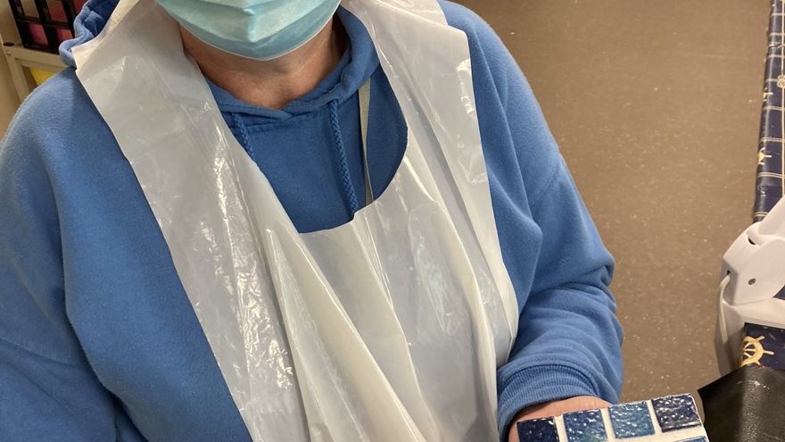 Blind veteran Sheila holding a square mosaic piece in tiles of different shades of blue