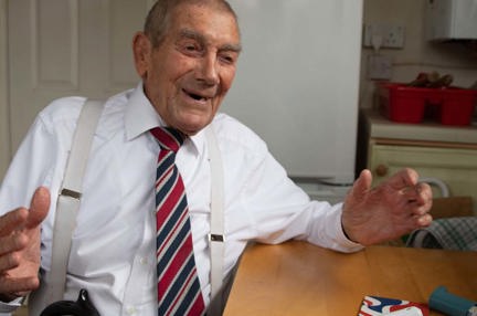 Blind veteran Eddie sitting in his kitchen, laughing while talking to his support worker