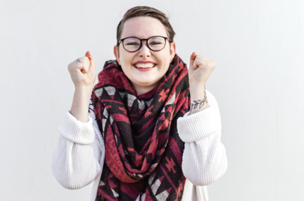 A young woman celebrating gleefully, with her hands raised in tight fists.