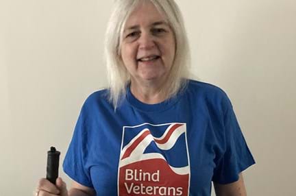 Kay is wearing her Blind Veterans UK t-shirt and is holding a white cane