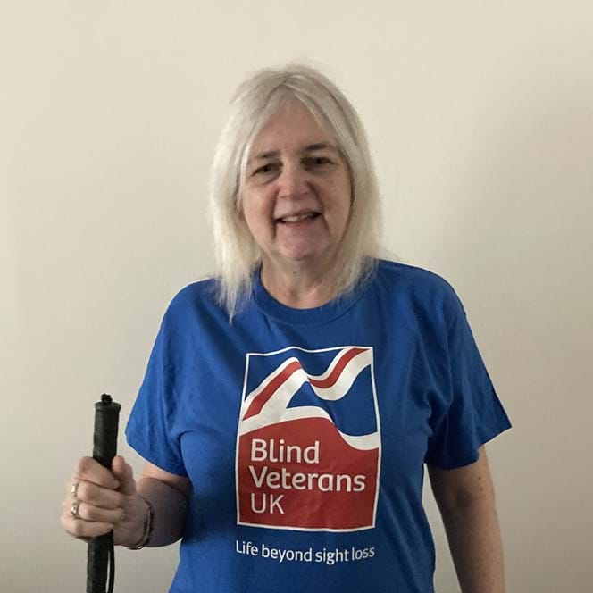 Kay is wearing her Blind Veterans UK t-shirt and is holding a white cane
