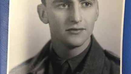 A black and white portrait of a young John during his days of service wearing his military uniform