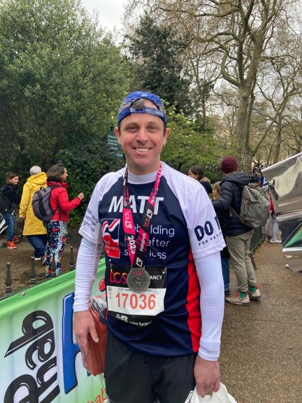 Matt smiling with his medal around his neck and wearing his Blind Veterans UK running top