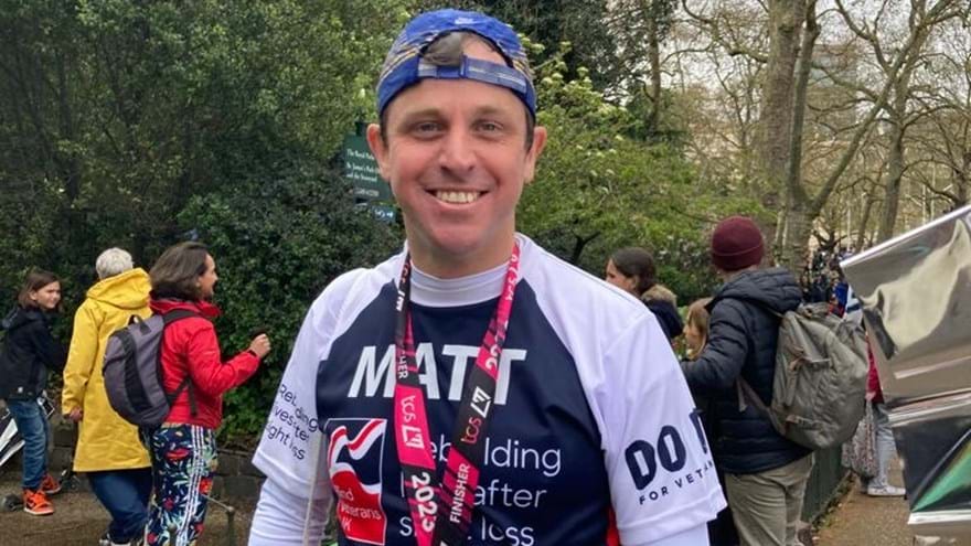 Matt smiling with his medal around his neck and wearing his Blind Veterans UK running top