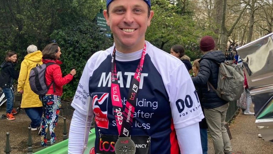 Matt smiling with his medal around his neck and wearing his Blind Veterans UK running top