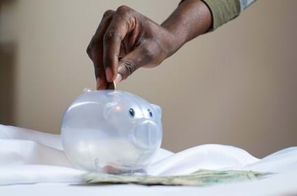 A photo of a person putting coin in a piggy bank