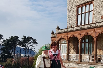 Michelle and Brian wearing German style clothing stood in front of the Llandudno Centre