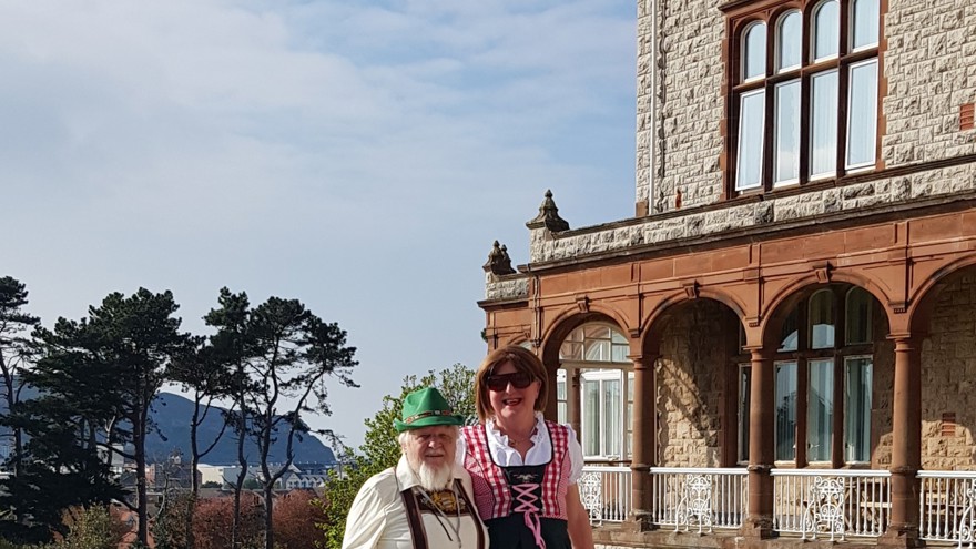 Michelle and Brian wearing German style clothing stood in front of the Llandudno Centre