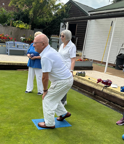 Veteran dressed in white playing bowls on a bowling green