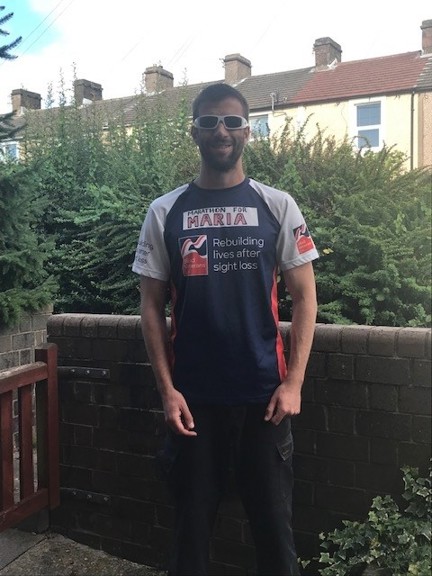 Darren stood in his garden wearing his Blind Veteran UK running top