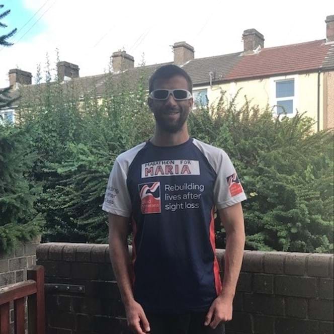 Darren stood in his garden wearing his Blind Veteran UK running top 