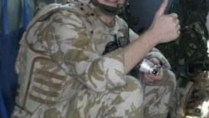 A young Ben in uniform sat in the back of an Army vehicle with his thumb up