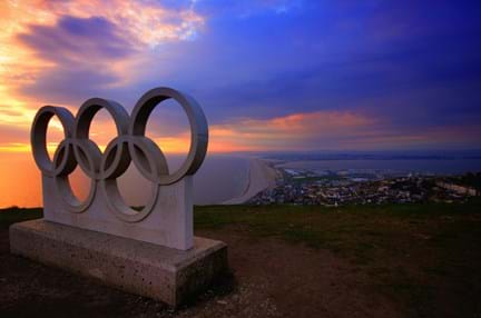 Olympics symbol on a grey concrete clock in front a sunset
