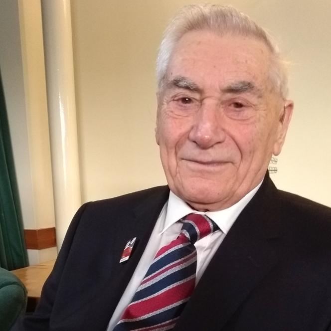 Blind veteran Bill in a suit, wearing a Blind Veterans UK badge and tie