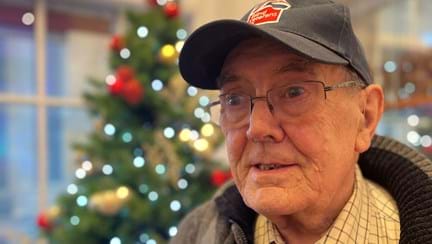 Blind veteran Alan standing beside a Christmas tree at our Llandudno Centre for Christmas