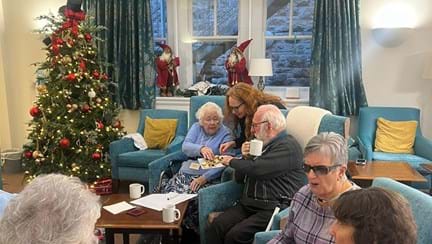 Blind veterans sitting in armchairs eating mince pies