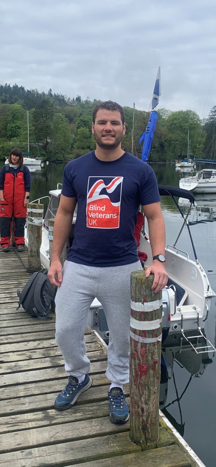 Johnny in a Blind Veterans UK t-shirt, standing near open water