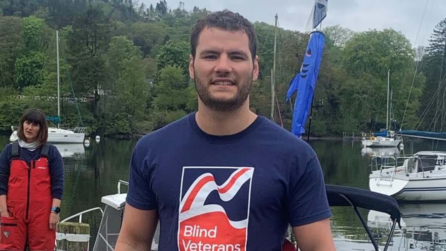 Johnny in a Blind Veterans UK t-shirt, standing near open water