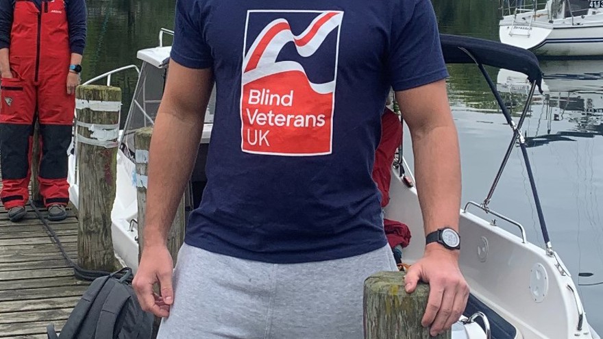 Johnny in a Blind Veterans UK t-shirt, standing near open water