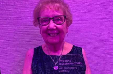 Gill smiles and looks into camera while posing with her award