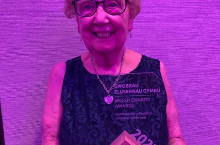 Gill smiles and looks into camera while posing with her award