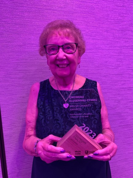 Gill smiles and looks into camera while posing with her award