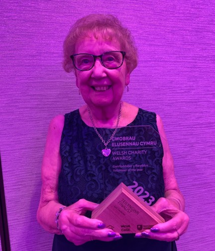 Gill smiles and looks into camera while posing with her award