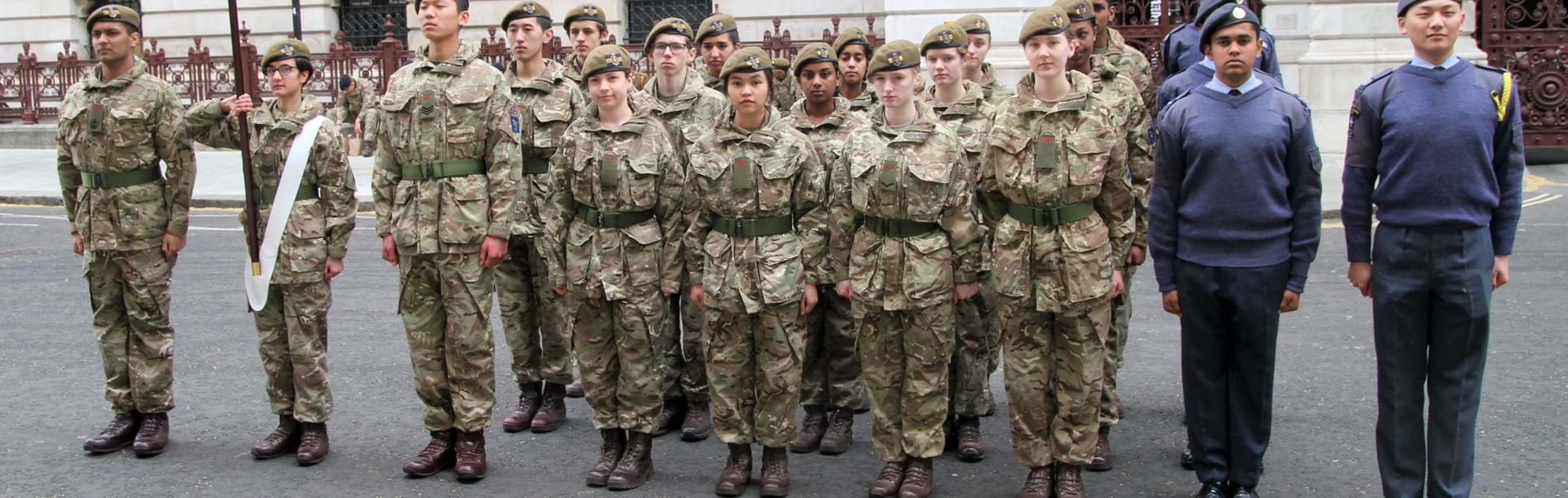 A group of cadets standing at attention in their uniform and berets 