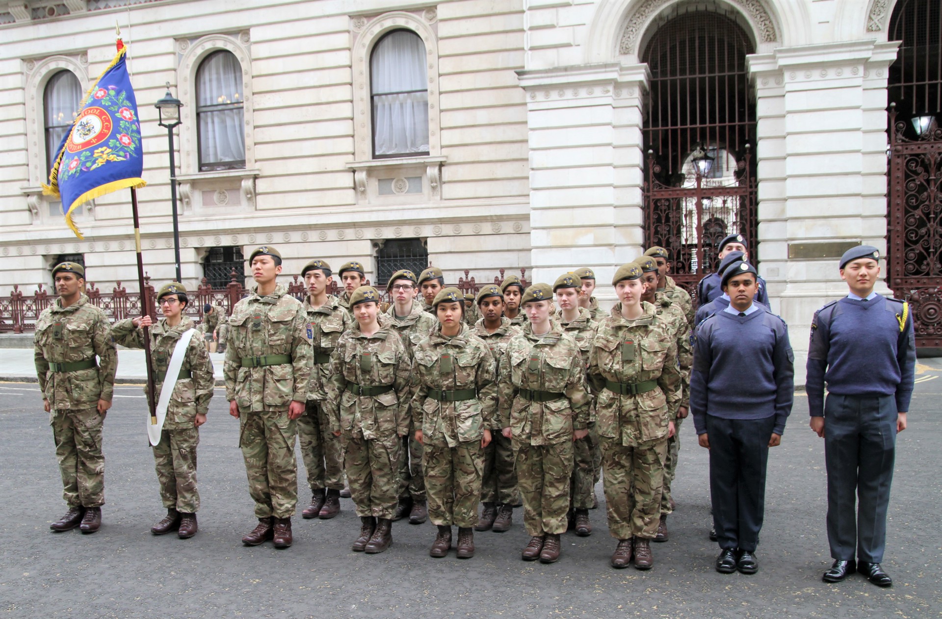 A group of cadets standing at attention in their uniform and berets