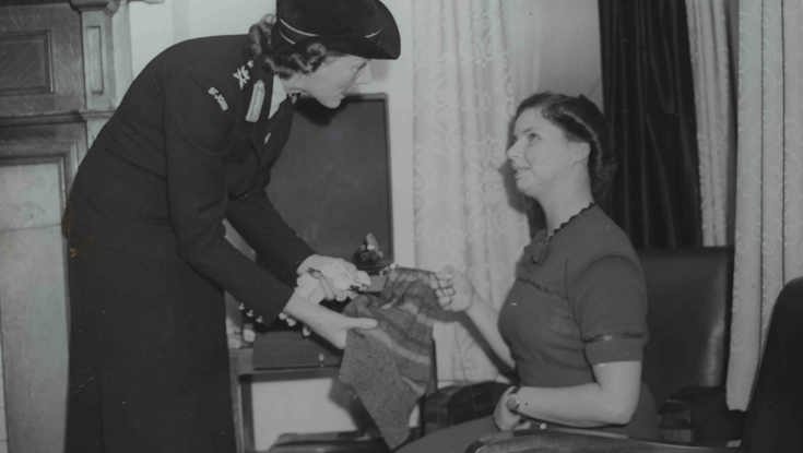 An archive photograph of blind veteran Barbara showing a woman in uniform her sewing work