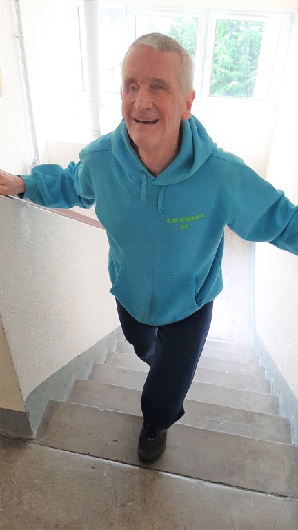 Blind veteran Jamie walking up stairs, smiling as he reaches the last step