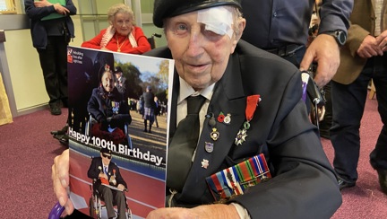 Blind veteran Ken smiling and holding up the card of himself and Margaret