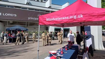 Our Blind Veteran's UK red gazebo set up at the event over a table with collection tins and information about the charity
