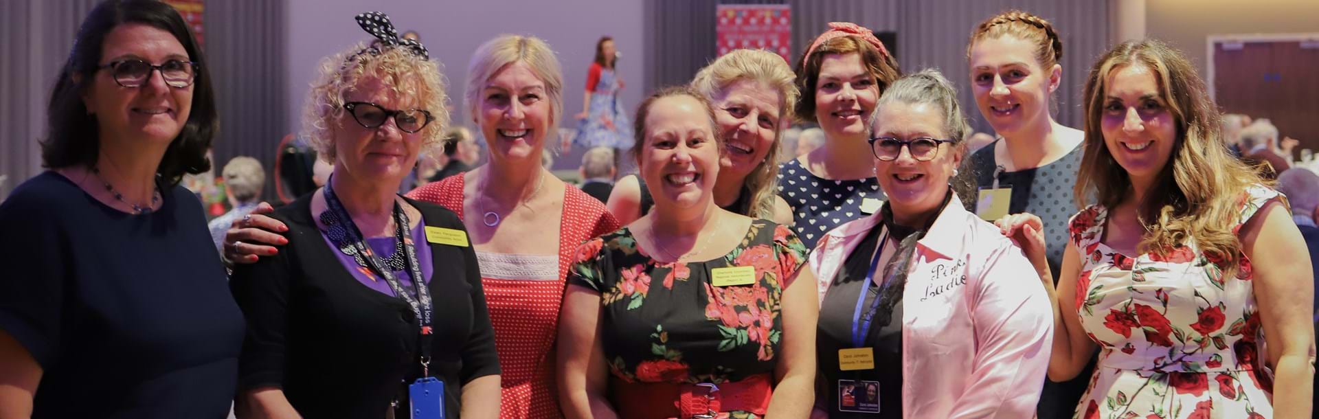 A group of nine Blind Veteran UK staff members at an event, gathered together and smiling