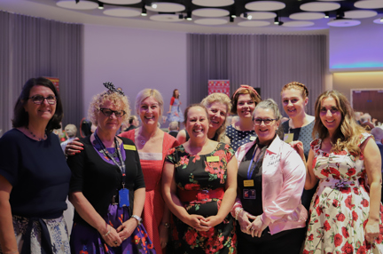 A group of nine Blind Veteran UK staff members at an event, gathered together and smiling