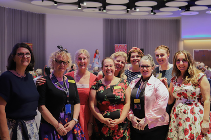 A group of nine Blind Veteran UK staff members at an event, gathered together and smiling