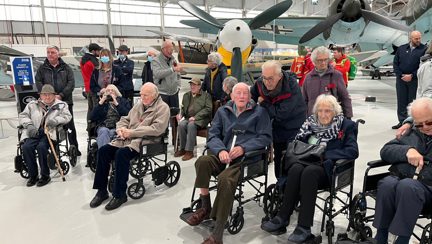 A photo of a group of blind veterans visiting the RAF Cosford Museum posed in front of the fighter jets