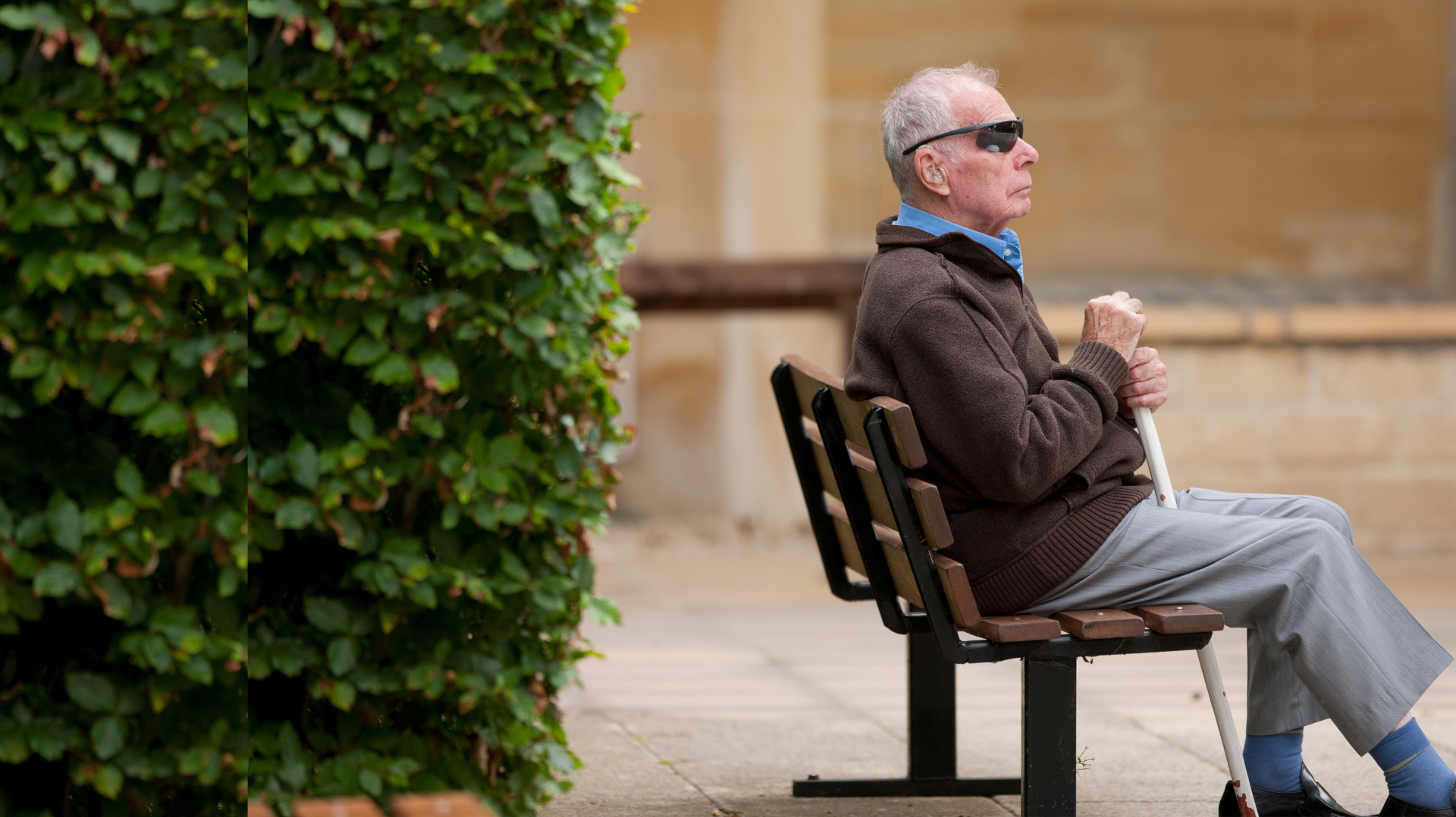 Blind veteran Tom, Korean War, sitting on a bench, with dark glasses and a white cane