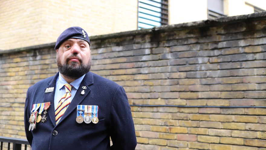 Blind veteran Simon wearing a navy suit, with his military medals and beret