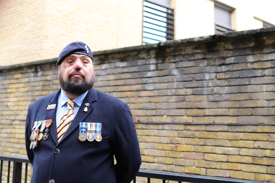 Blind veteran Simon wearing a navy suit, with his military medals and beret