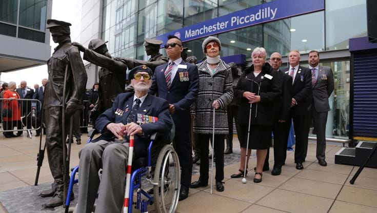 A photo of seven blind veterans next to the Victory Over Blindness statue