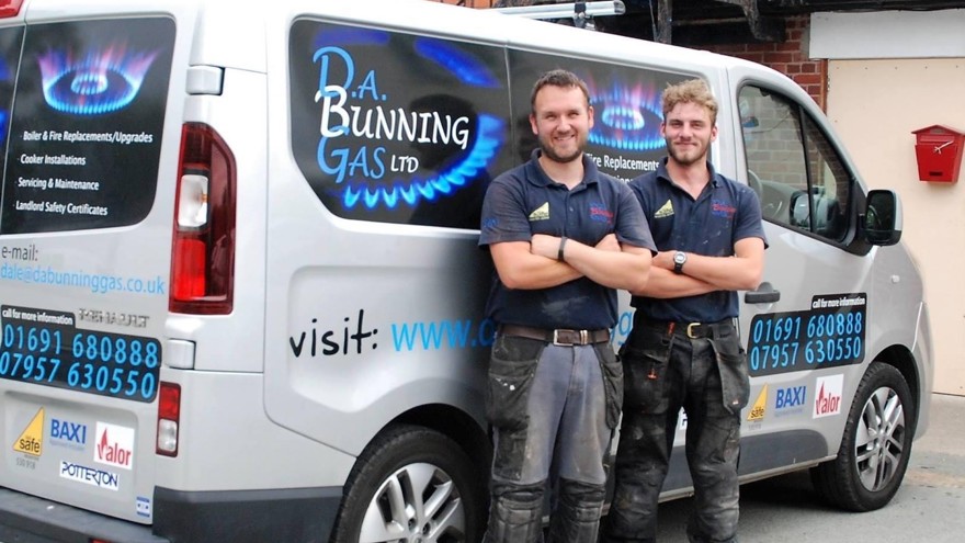 Charity supporter Dale and his colleague, standing in front of their work van, smiling.