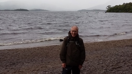 Gary pictured on a pebbled beach with the sea behind him on a cloudy day